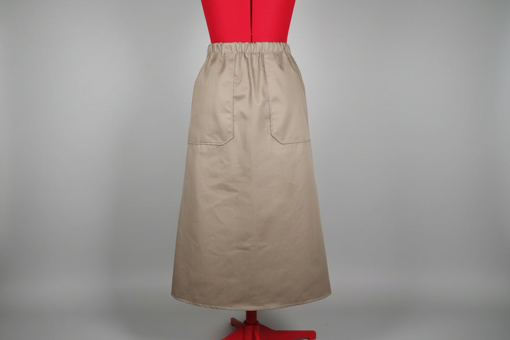 Beige skirt on a red stand against a white door.